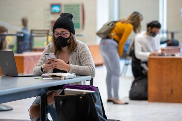 Student studying in MUSC. Wearing McMaster branded face mask.