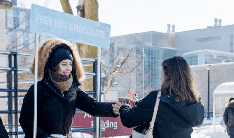 Student giving out hot chocolate in winter.