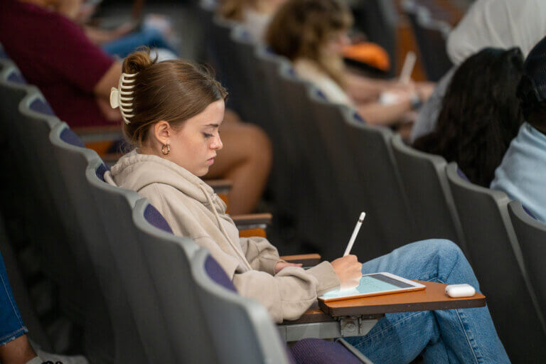 Student writing in a lecture hall