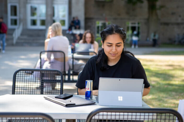 Students working at laptops outside on McMaster campus.