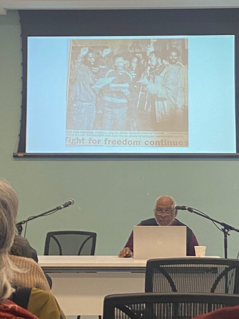 Dr. Gary Warner on a laptop. The projector image is a newspaper clipping with the title, fight for freedom continues.