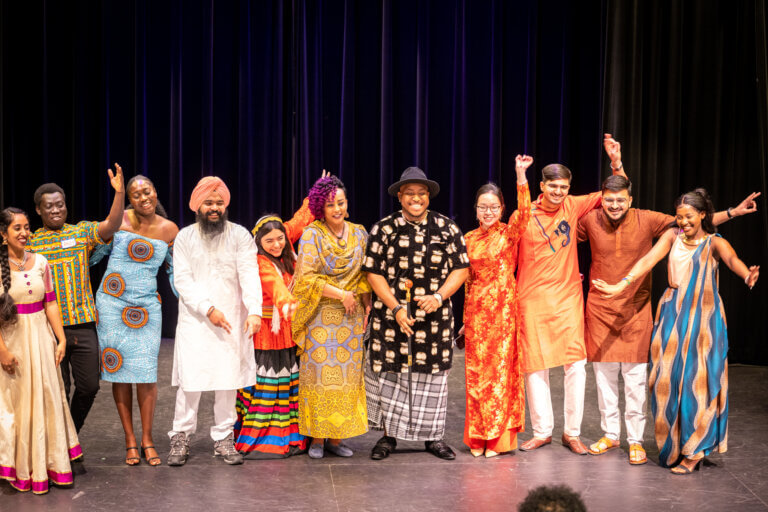 Students and staff onstage wearing cultural clothing.